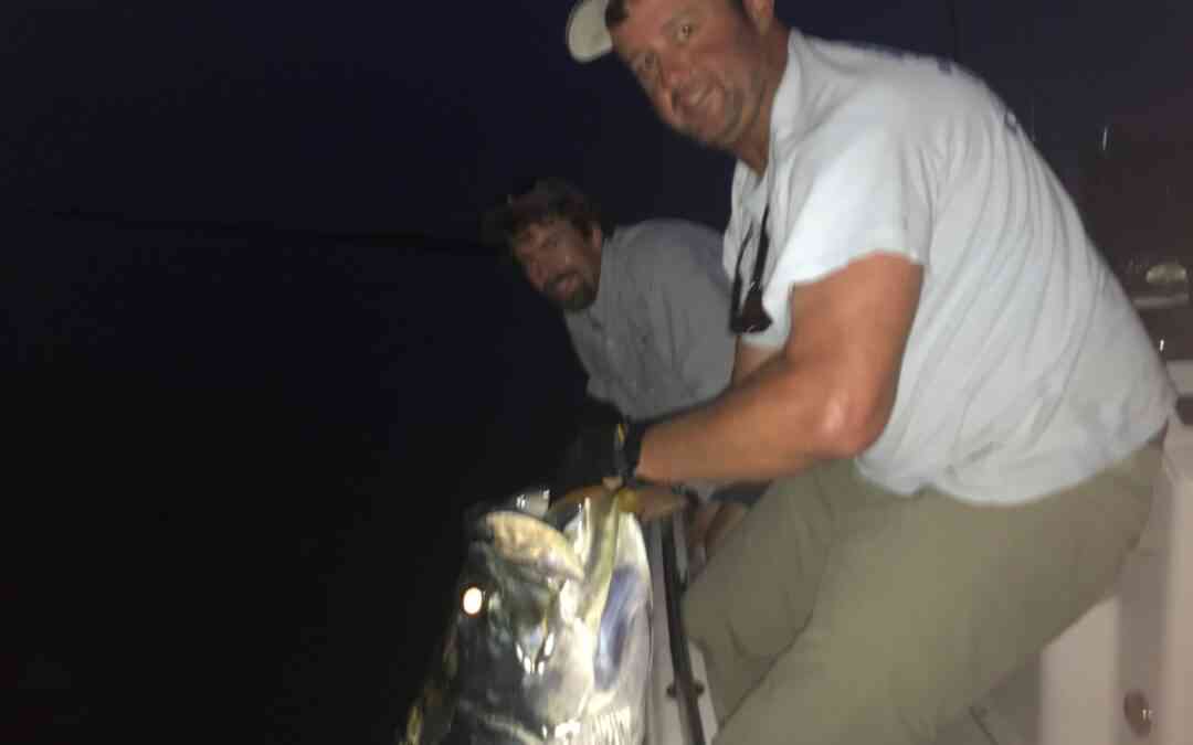 a fisherman with a tarpon at night