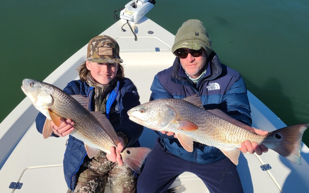 father and son holding two redfish