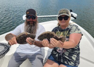 man and woman holding two flounder