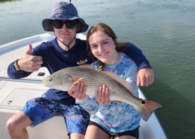 man with girlfriend holding a redfish