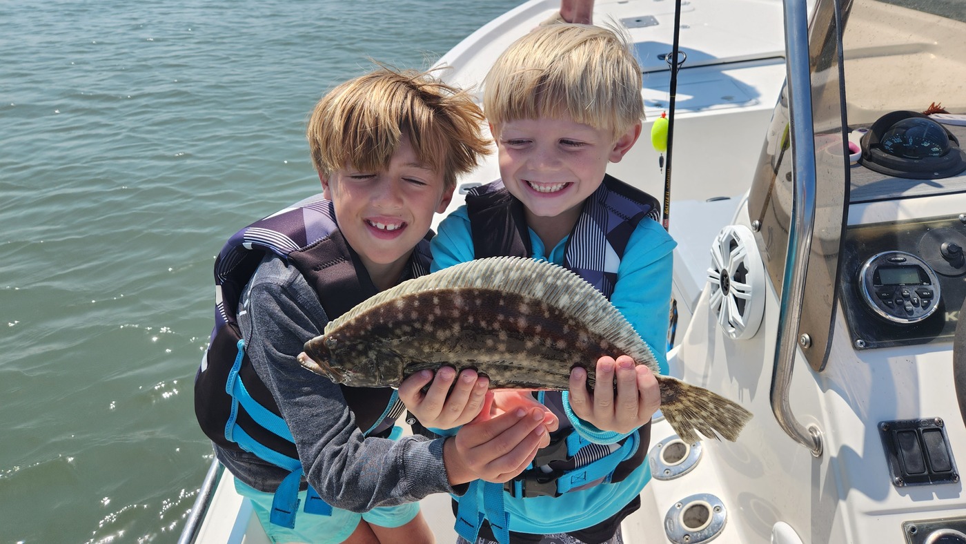 two kids holding flounder