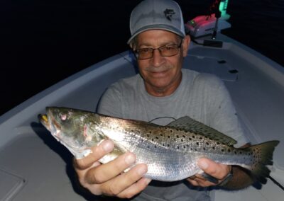 man holding speckled trout caught on topwater
