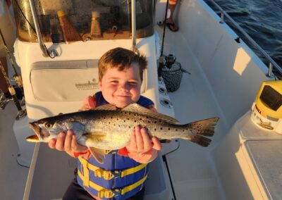 kid holding speckled trout fish