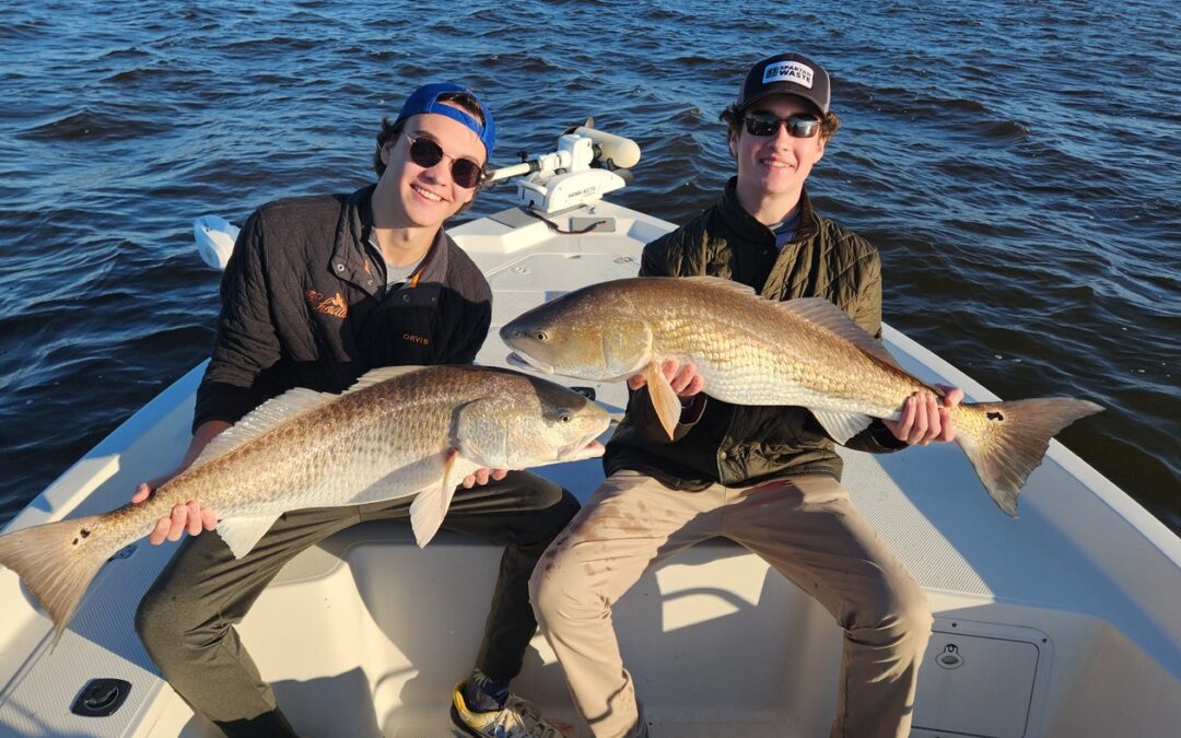 two fishermen holding two big bull red drum