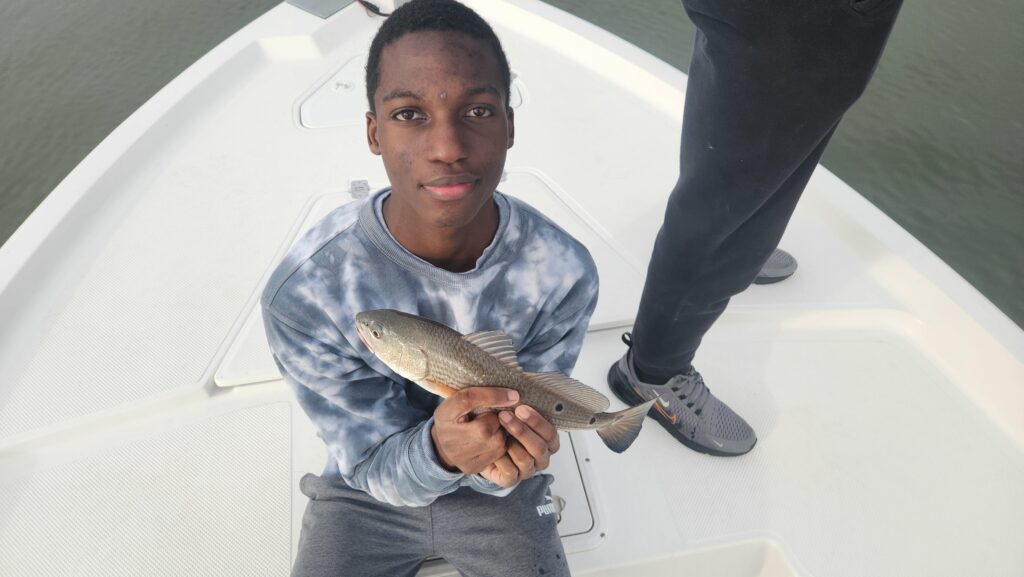 young man holding redfish in north myrtle beach, south carolina